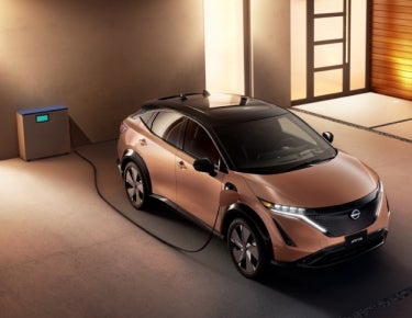 Nissan ARIYA plugged-in and charging outside a home | Jim Click Nissan in Tucson AZ